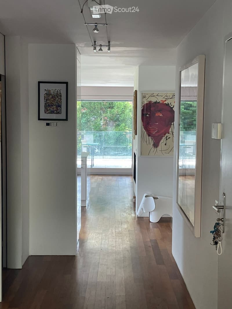 wooden floor, white walls, mounted artwork, mirror, door, balcony with glass railing