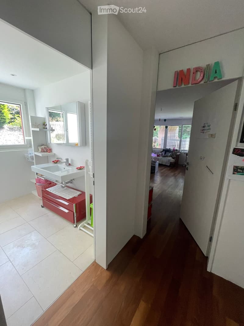 Bathroom with sink, mirror, red cabinets, tiled floor, open door, hallway
