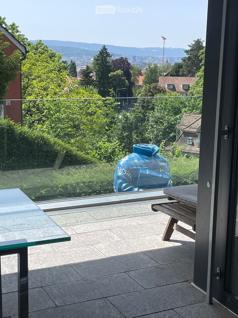 balcony with glass railing, large glass window, wooden bench, glass table, view to landscape and buildings