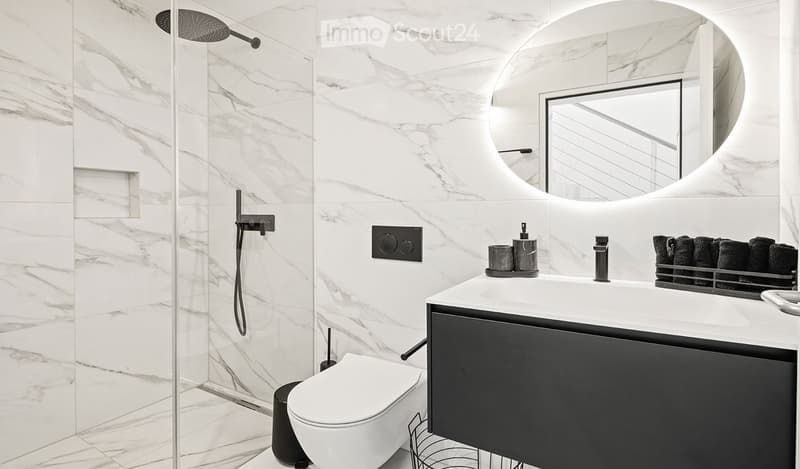 Modern bathroom with marble walls and floor, featuring a toilet, sink with a sleek faucet, a large mirror, and a shower area with a modern showerhead.