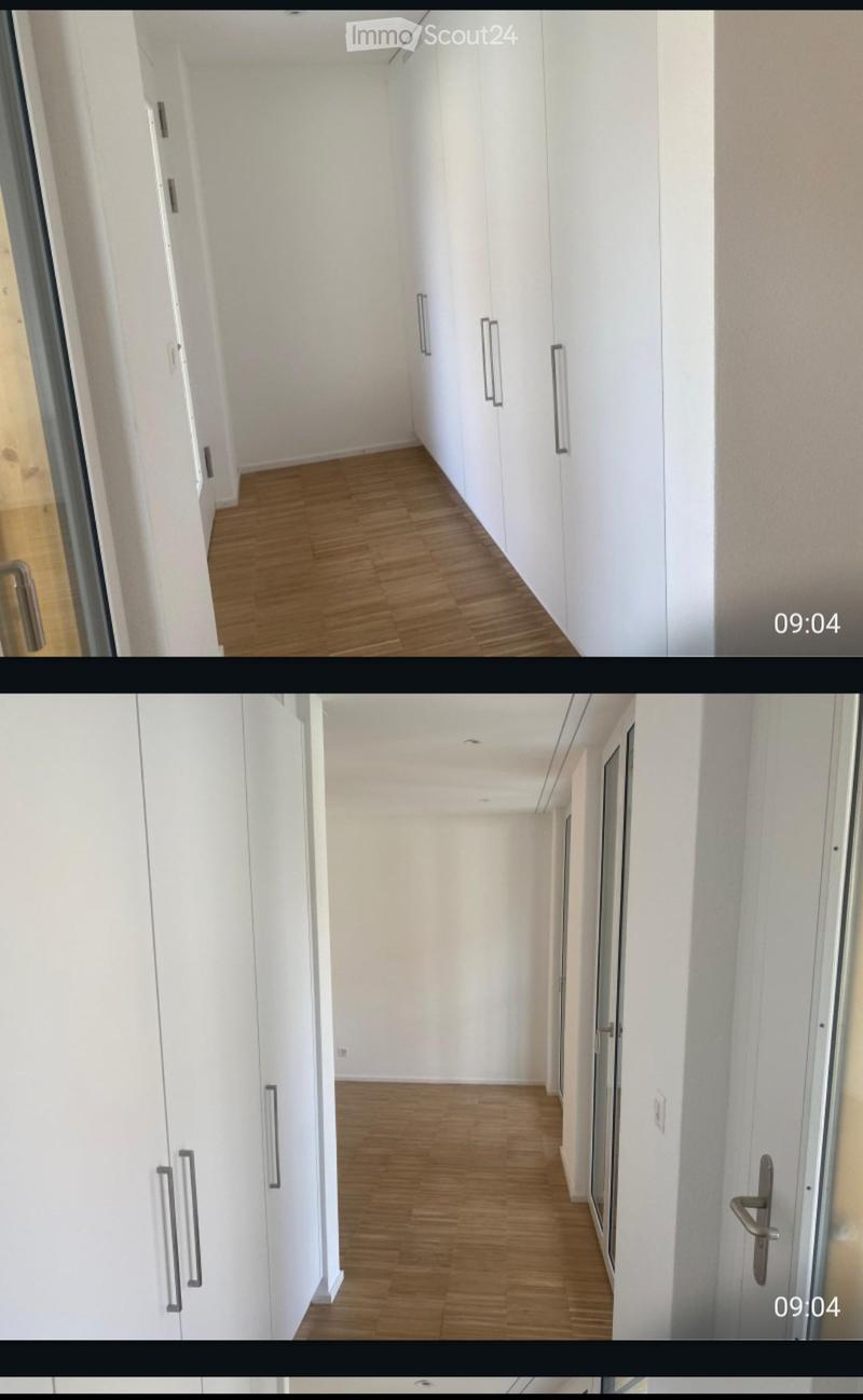 Clean, modern hallway with light wooden flooring, white walls, and built-in white cabinets with silver handles. The space is well-lit and appears unfurnished.