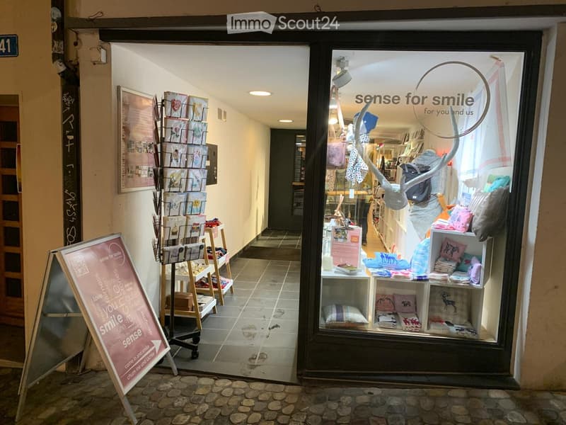 Storefront with shelves displaying pillows, cards, and other items. A signboard outside advertises the store's theme of 'sense for smile.'