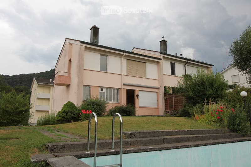 Two-story house with beige and pink exterior, multiple windows, balconies, and a swimming pool in the front yard.