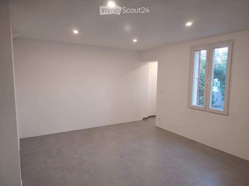 Empty room with white walls, tiled floor, and a large window with a view of greenery. No furniture or equipment is present.