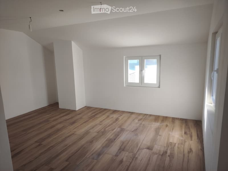 Empty room with white walls, wooden flooring, and a single window with white frame. No furniture or equipment present.