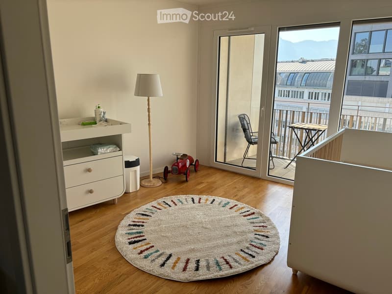 Child's room with wooden floor, round rug, floor lamp, toy car, and balcony with outdoor furniture and scenic view.