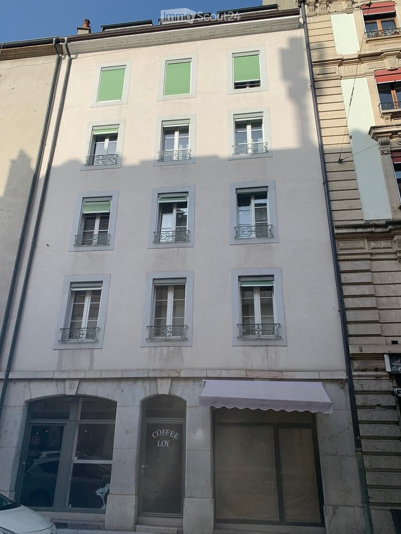 Four-story building with light-colored facade, multiple windows with decorative metal balconies, and a storefront labeled "COFFEE LOY" on the ground floor.
