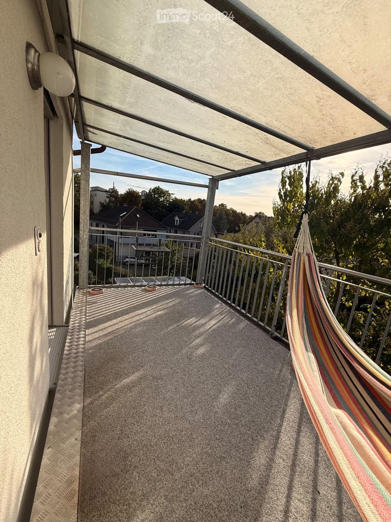 Balcony with a hammock, metal railing, and a view of the neighborhood.