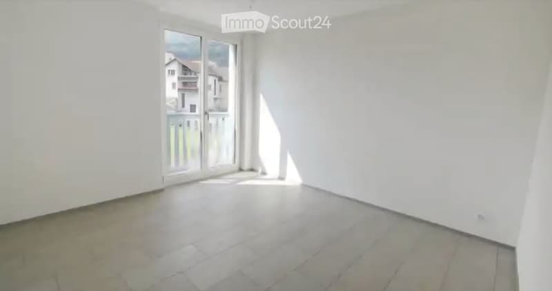 Empty room with white walls, tiled floor, and large sliding glass door leading to a balcony.