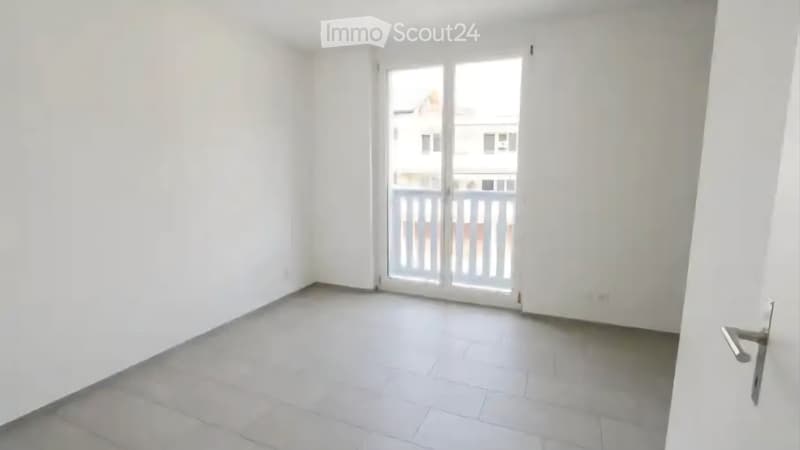 Empty room with white walls, tiled floor, and a sliding glass door leading to a balcony.