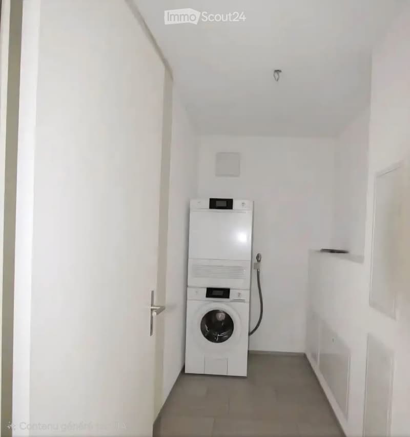 A small, white-walled room with a washing machine and dryer unit positioned against the wall.