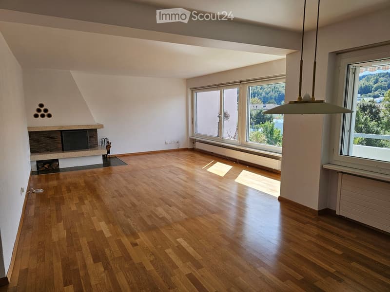 Empty room with wooden flooring, large windows, and a fireplace. No furniture or equipment present.