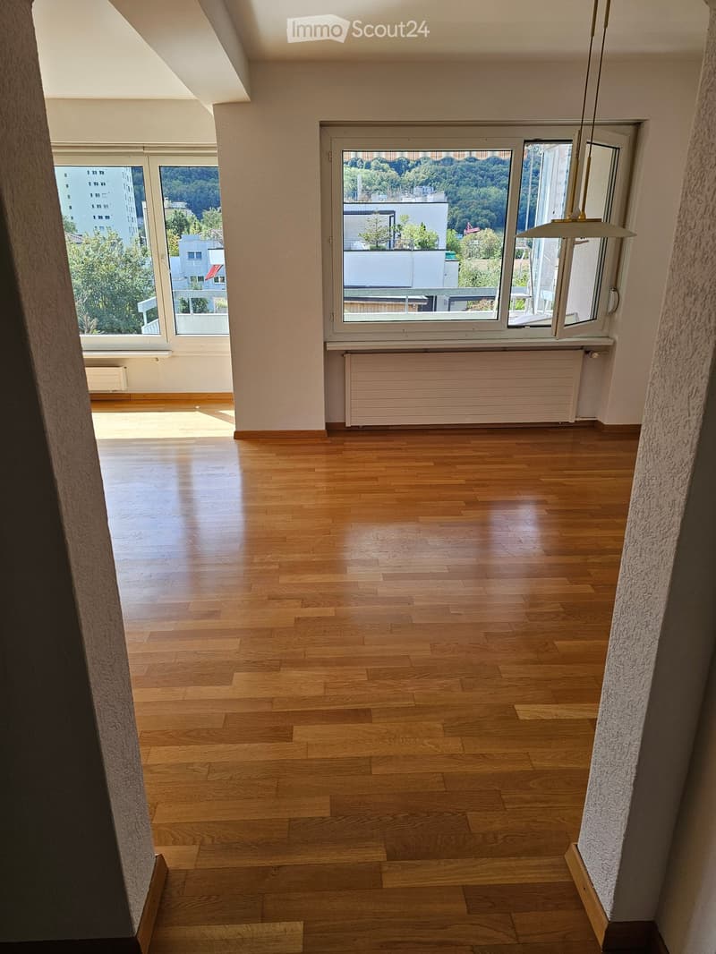 Empty room with wooden flooring, large windows, and radiators. No furniture or equipment present.