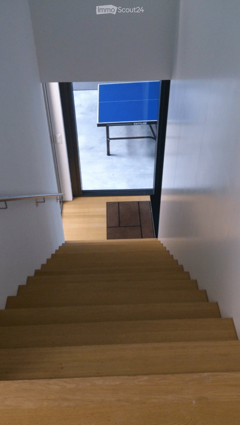 Wooden staircase leading up with white walls and a glass door at the top, revealing a blue object in the background.