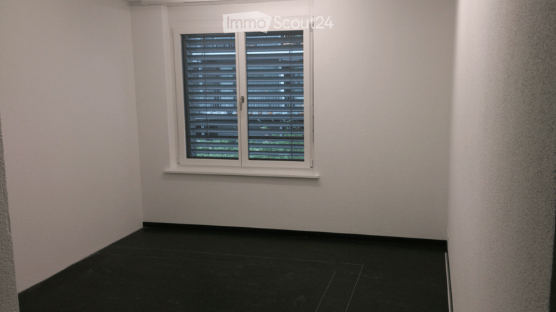 Empty room with black tiled floor, white walls, and a window with blinds.