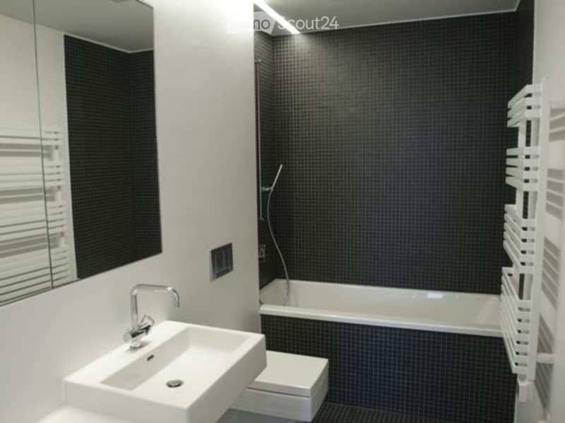 Modern bathroom with black tiled walls, white fixtures, and a sleek design.