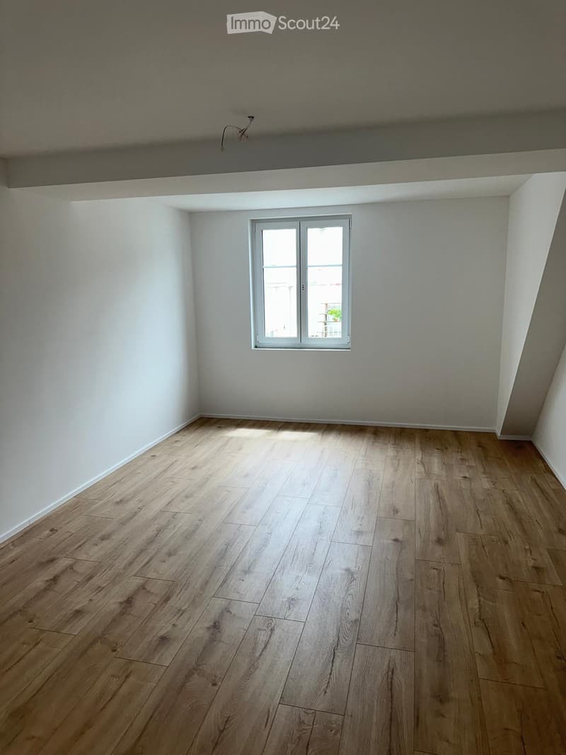 Empty room with wooden flooring and white walls, featuring a single window with white frame and glass panels.