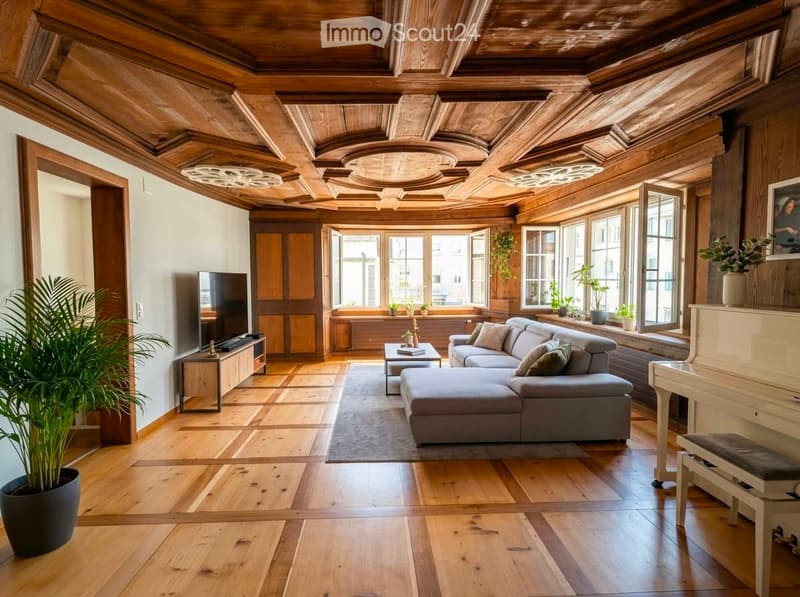 Living room with wooden ceiling, large windows, grey sectional sofa, coffee table, piano, and potted plants.