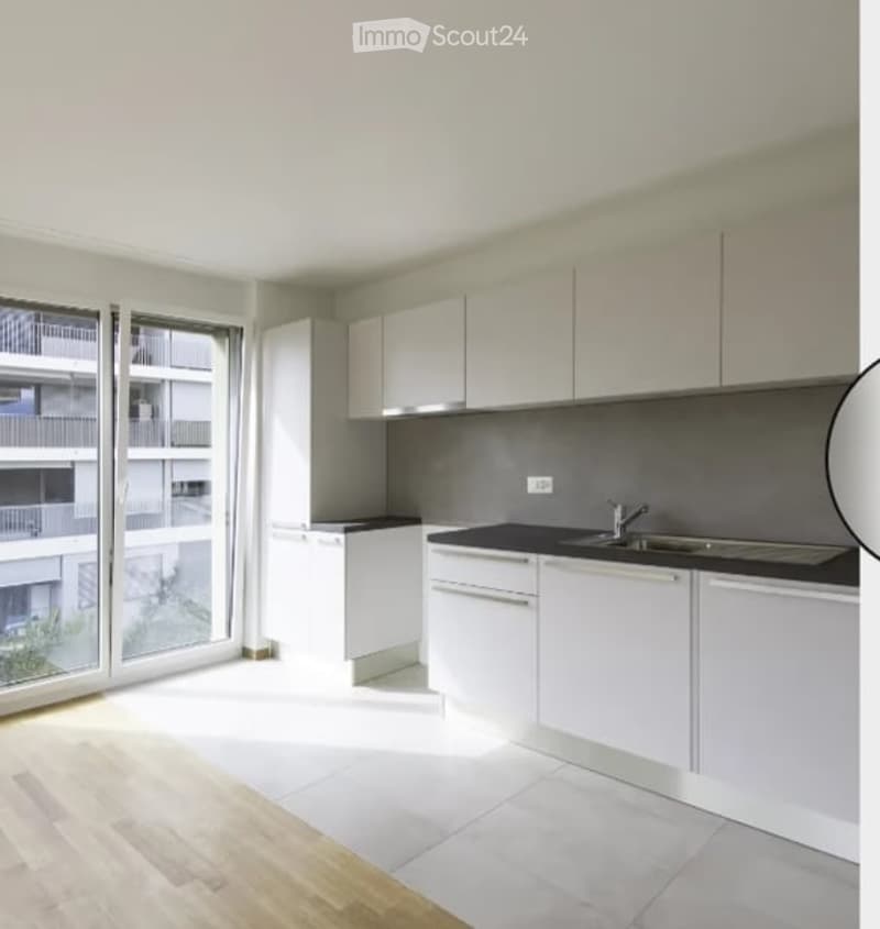 Modern kitchen with white cabinets, black countertops, and a large window offering a view of the balcony.