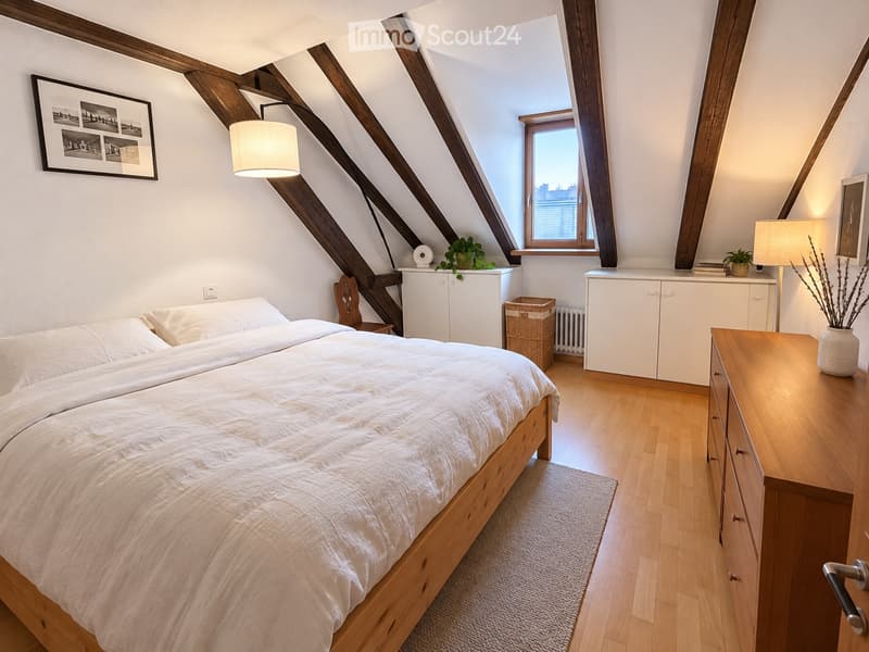 Cozy attic bedroom with wooden slanted ceilings, a large bed with white bedding, a nightstand, a wooden cabinet, a wicker basket, and decorative plants.