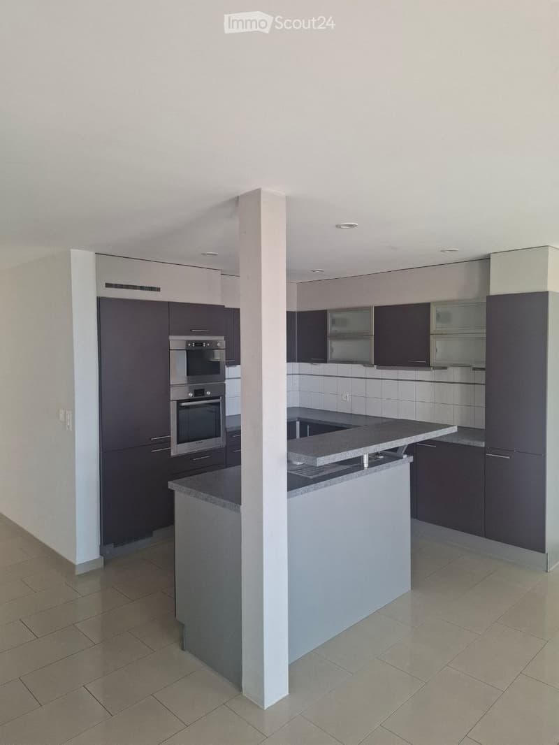 Modern kitchen with dark cabinets, stainless steel oven, and a central island with a granite countertop.