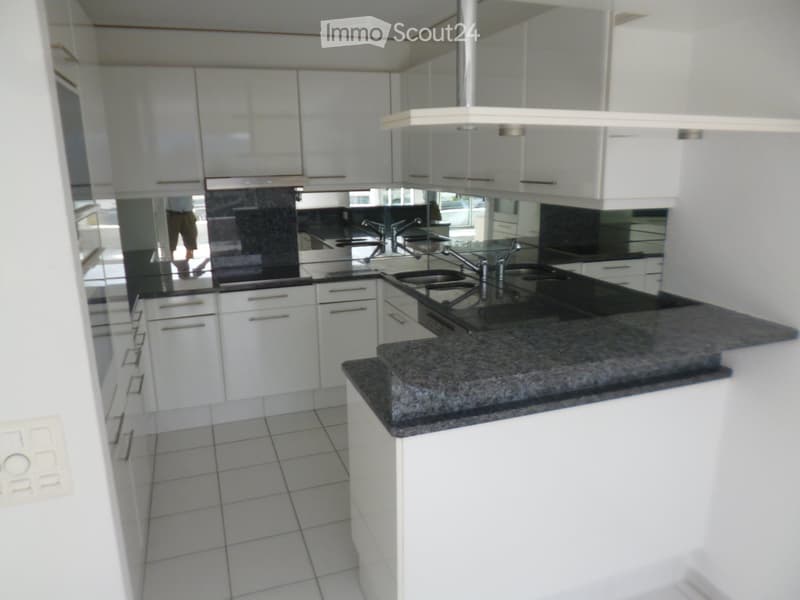 Modern kitchen with white cabinets, granite countertop, and stainless steel sink.