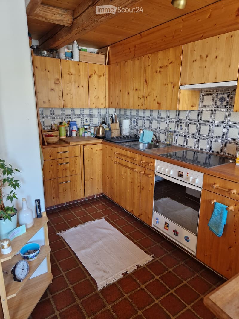 Cozy kitchen with wooden cabinets, tiled backsplash, and a variety of appliances and items on the countertops.