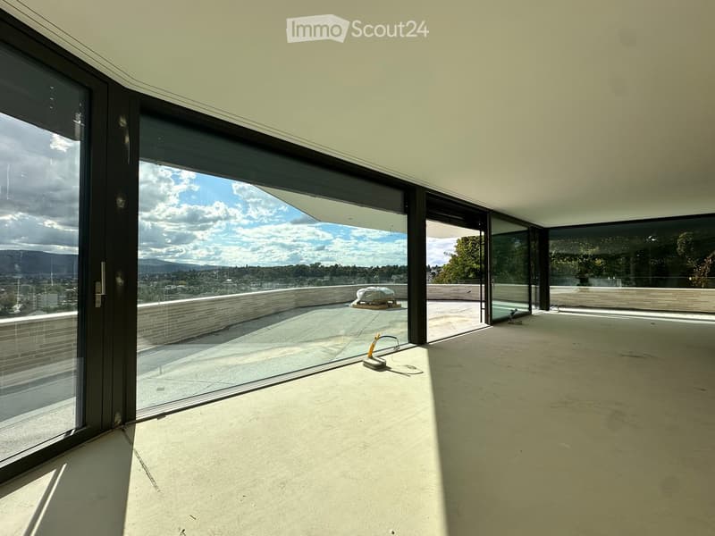 Empty room with large glass sliding doors leading to a rooftop terrace, concrete floor, and modern white ceiling.