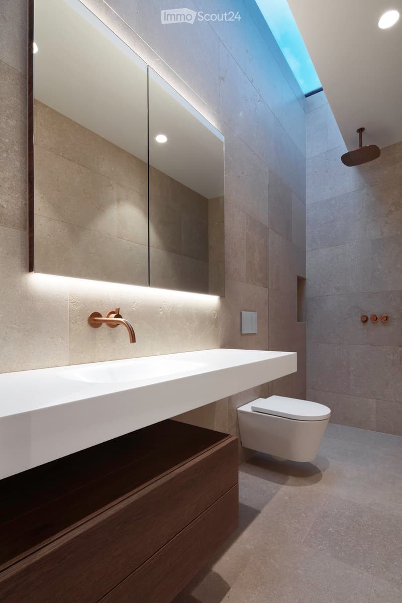 Bathroom with large mirror, white sink, white toilet, modern fittings, skylight, wooden cabinet, tiled wall
