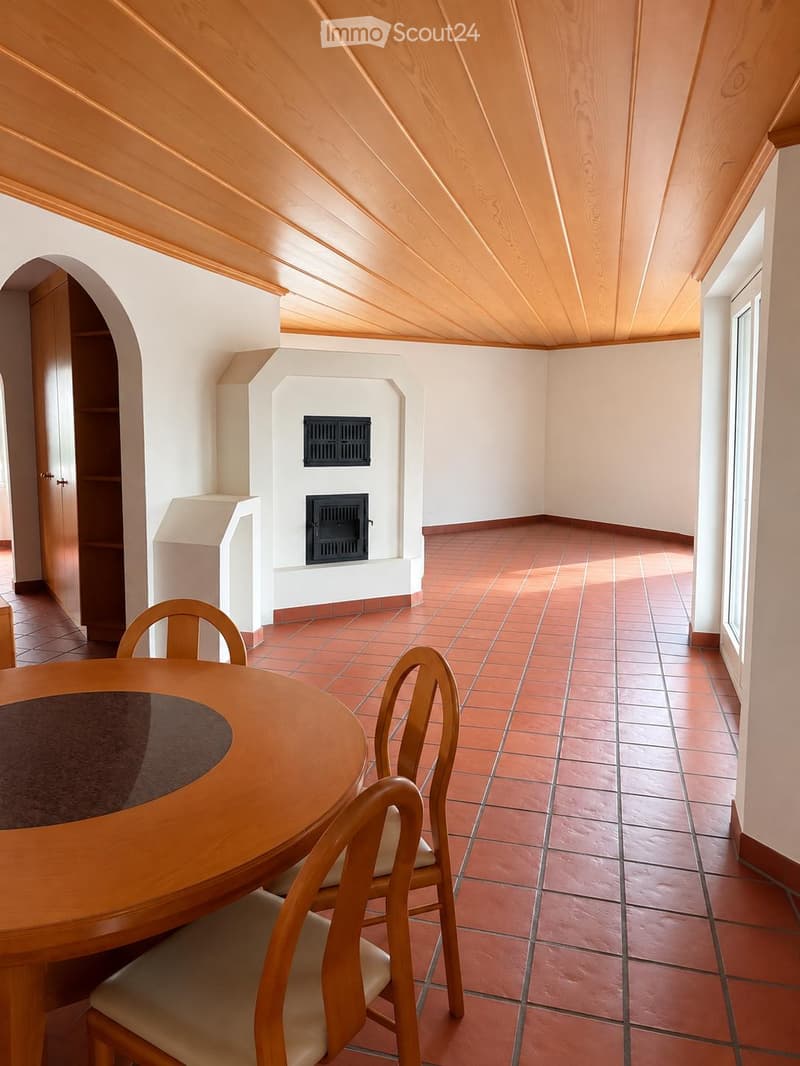 Dining area with a wooden dining table, chairs, and a fireplace in the background.