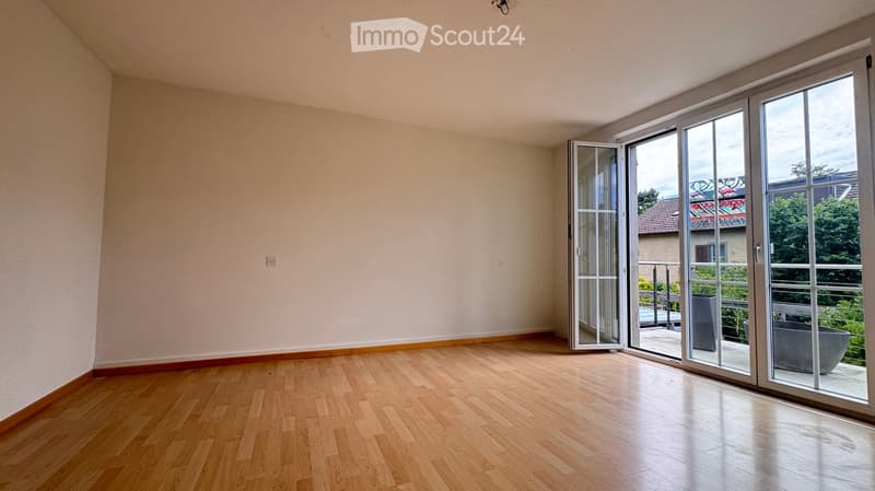 Empty room with wooden flooring and large sliding glass doors leading to a balcony.