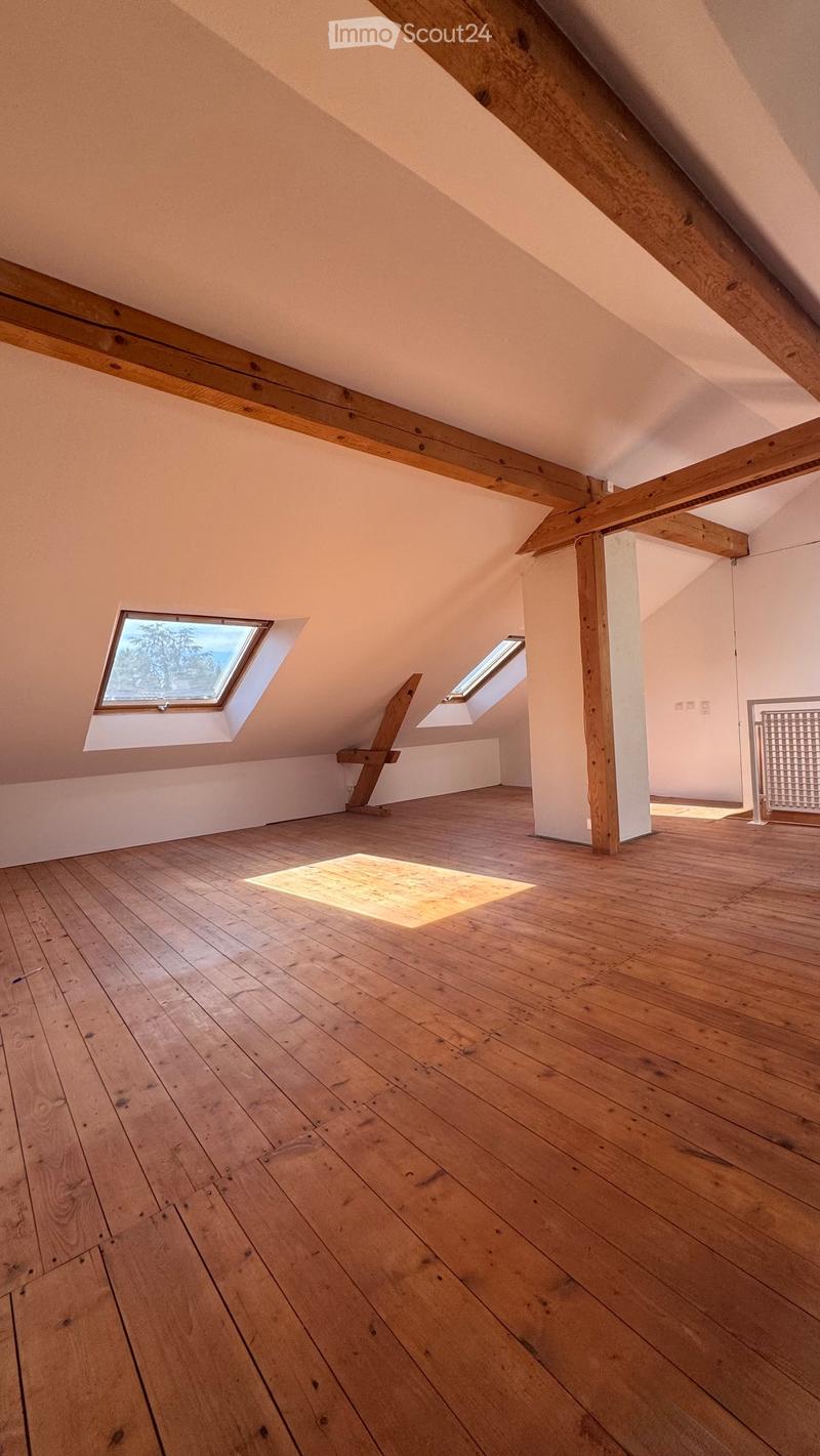 Empty attic space with wooden floors, exposed wooden beams, and skylight windows allowing natural light to enter.