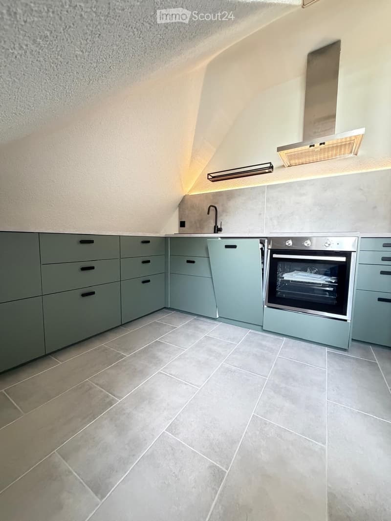 Modern kitchen with grey cabinets, tiled floor, and stainless steel oven. Features a sleek design with built-in lighting and a contemporary faucet.