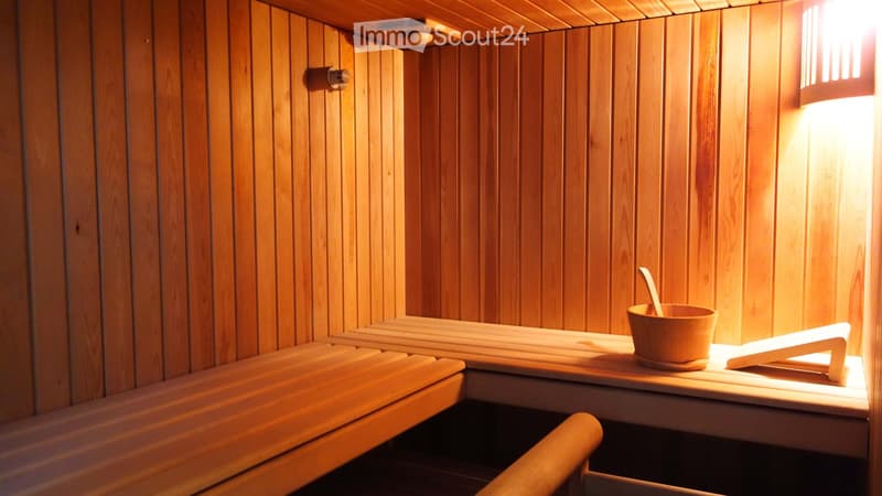 Wooden sauna with benches, a bucket, and a wooden spoon on a small table.