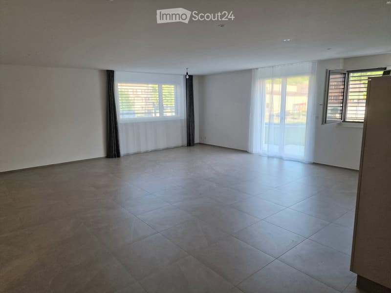 Empty room with tiled floor, white walls, large windows with blinds, and curtains. No furniture or equipment present.