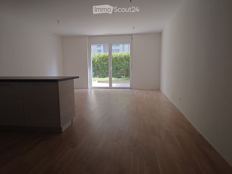 Empty room with wooden flooring, white walls, and a sliding glass door leading to an outdoor area.