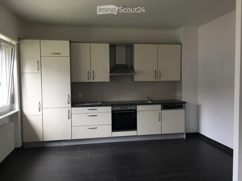 Modern kitchen with white cabinets, stainless steel appliances, and dark tiled flooring.