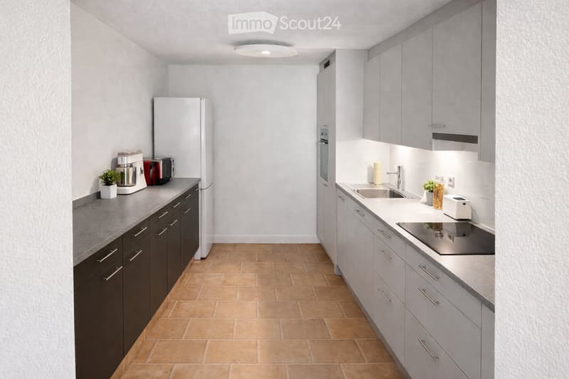 Modern kitchen with grey cabinets, dark lower cabinets, light countertops, stainless steel appliances, and a tiled floor.