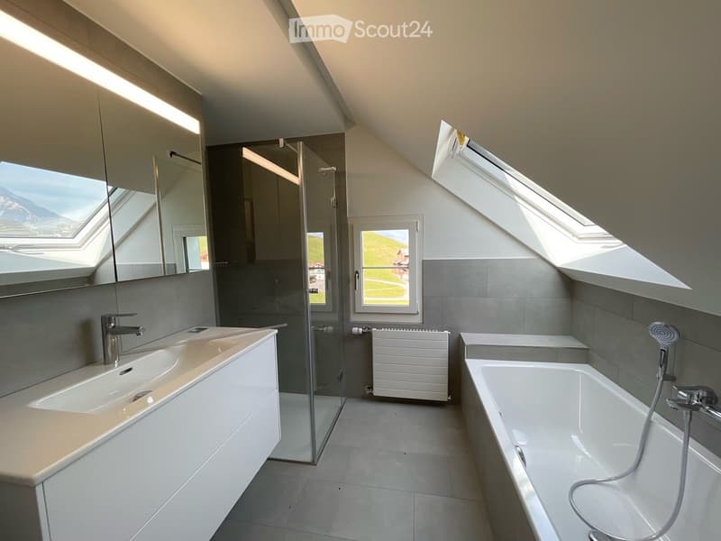 Modern bathroom with a double sink, bathtub, large windows, and a scenic view outside.