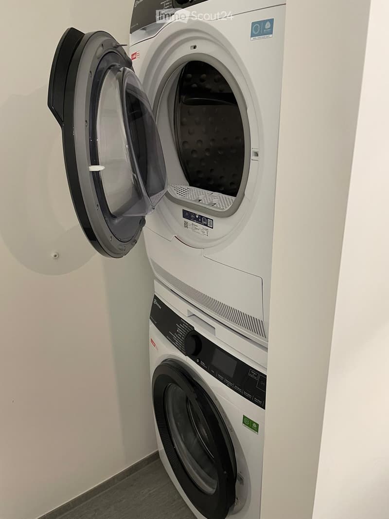 Modern bathroom with a white washing machine and dryer unit, both with open doors showing the interior.