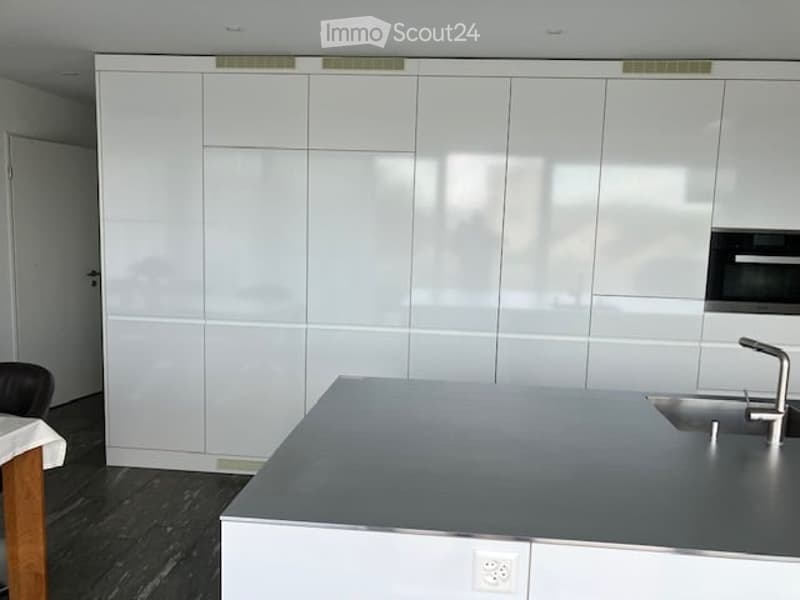 Modern kitchen with white cabinets, stainless steel sink, and a sleek countertop.