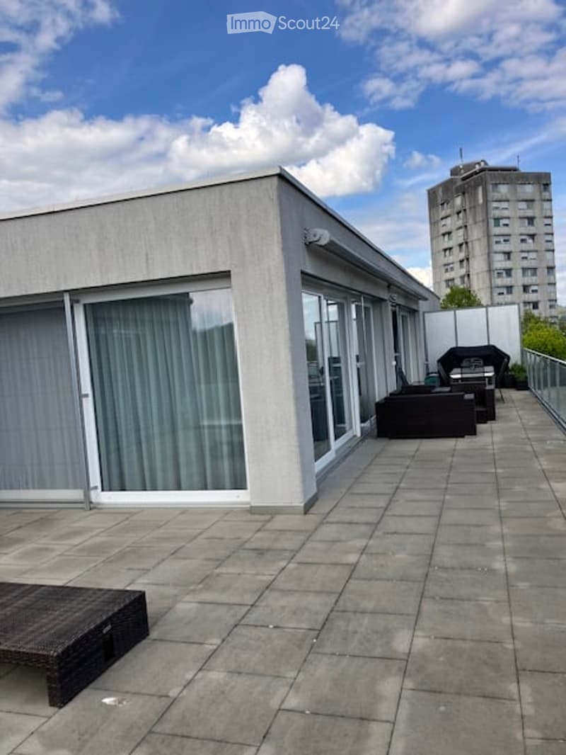 Roof terrace with large sliding glass doors, tiled floor, and outdoor furniture including a sofa and a table.