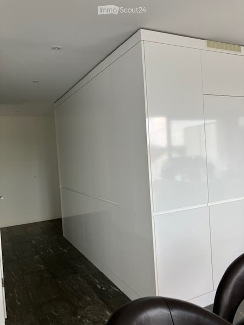 Empty room with white walls, dark wooden floor, and a large white cabinet. No furniture or equipment visible.