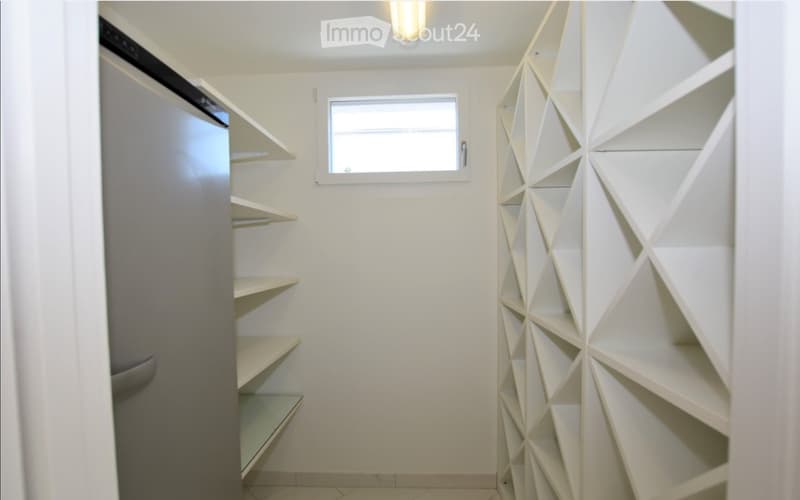 Empty closet with built-in shelving units and a small window, featuring modern geometric shelving design.