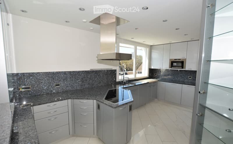 Modern kitchen with white cabinets, granite countertops, stainless steel appliances, and a large window providing natural light.