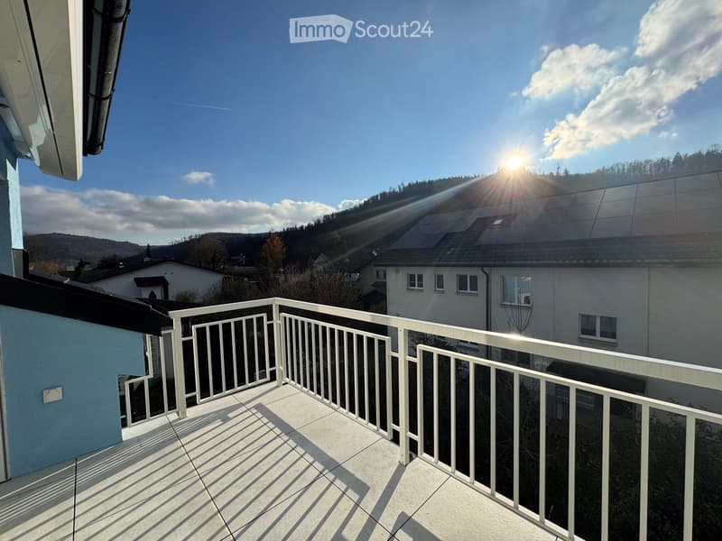 Balcony with white metal railing, tiled floor, and a view of the surrounding area with houses and hills.