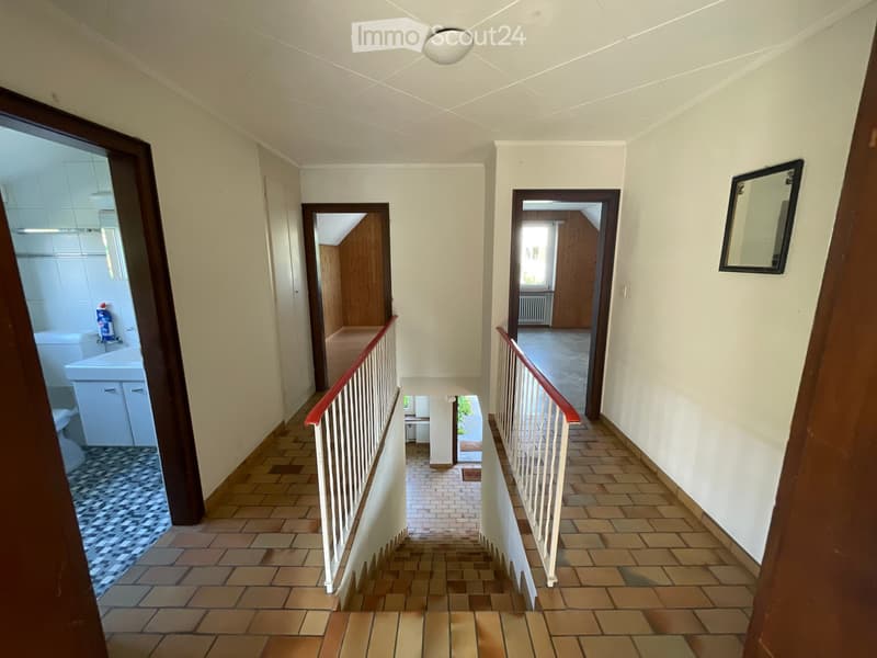 Staircase with tiled steps and white railings, leading to multiple rooms including a bathroom and a living area.