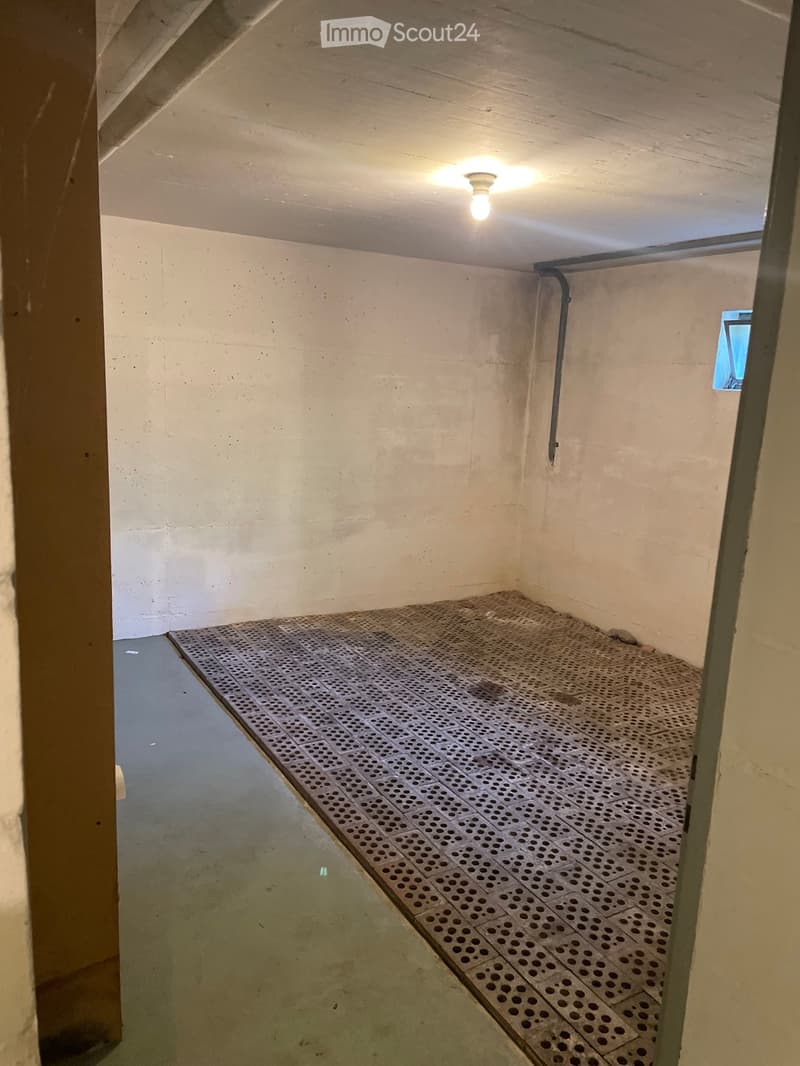 Empty room with concrete walls, a metal grated floor, and a small window. No furniture or equipment is present.