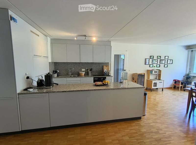 Modern kitchen with white cabinets, granite countertop, stainless steel appliances, and a small dining area with a table and chairs.