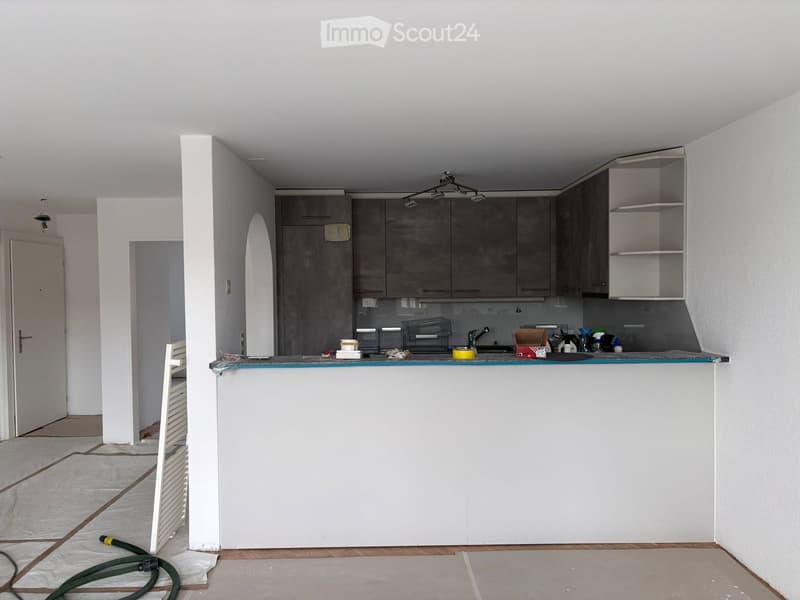 Empty kitchen area with unfinished walls, cabinets, and a countertop. No furniture or appliances are present.